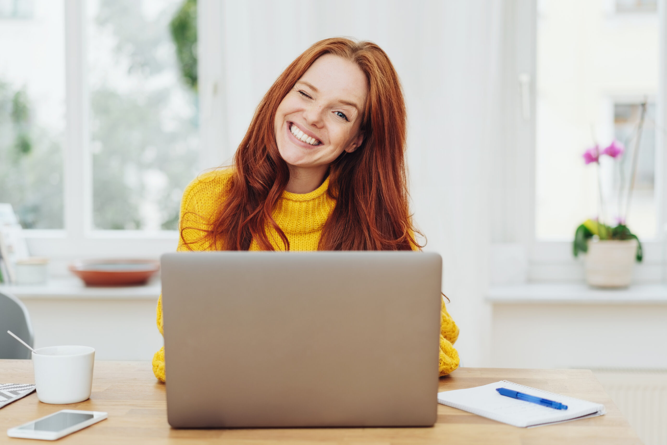 Young happy red-haired woman using laptop